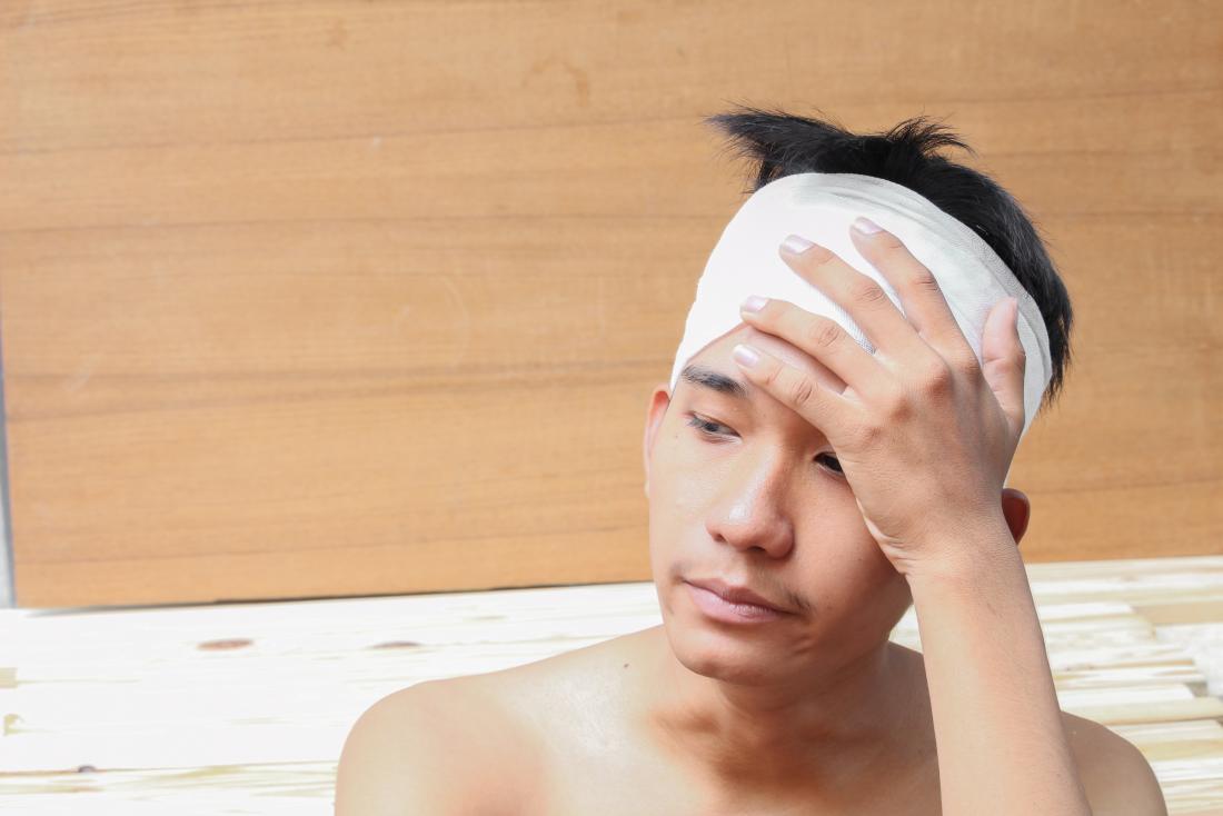 man with head injury from cat accident holding bandage on head